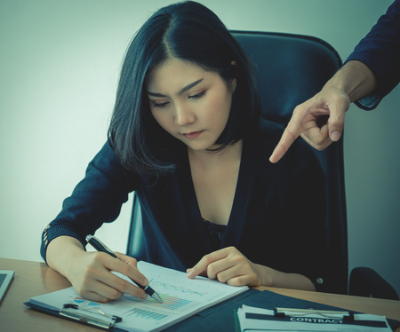 Female office worker is working under pressure from supervisorの写真素材