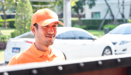 Orange uniform Delivery man is waiting at the gate の写真素材