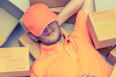 Package delivery person sleeping around order boxesの写真素材