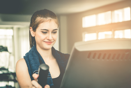 Woman is looking at exercise machine display with happy faceの写真素材