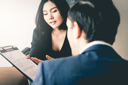 Female mananger is offering a new employee to sign work contractの写真素材