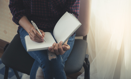 Female casual creative designer worker is writing note on notebookの写真素材