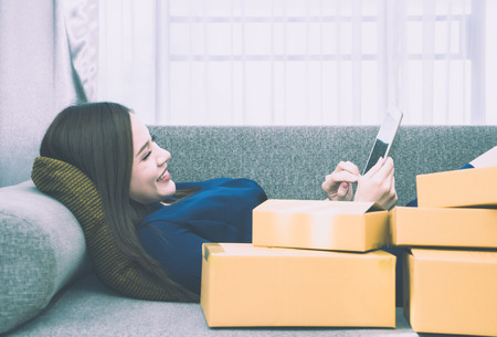 Asian Girl is addited to online shopping, full of deliveried boxesの写真素材