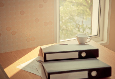 Business folder files and coffee on desk by the windows