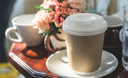 Paper coffee mug on table in morning lightの写真素材