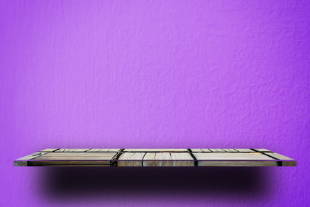 Empty wooden shelf on purple cement wallの写真素材