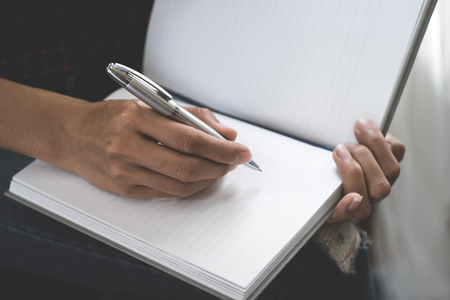 Female casual creative designer worker is writing note on notebookの写真素材