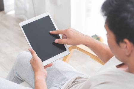 Casual man is using empty tablet screen for tablet application mock upの写真素材