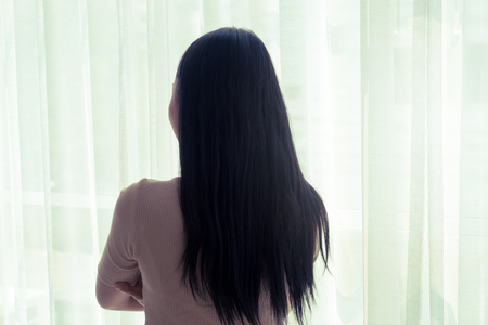 silhouette shadow of asian woman by bright windowsの写真素材