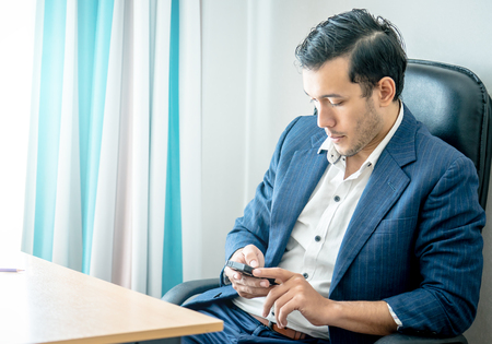 Business man is using mobile phone in office deskの写真素材