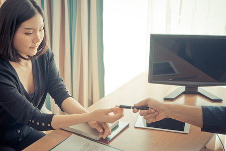 Business man is handing pen to a woman for contract signingの写真素材