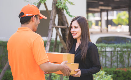 Delivery man in orange bringing woman the packageの写真素材