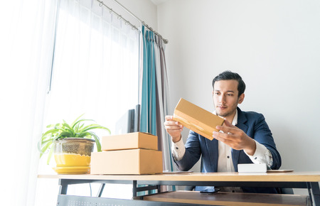 Thoughtful business man is looking at his packaging delivery boxesの写真素材
