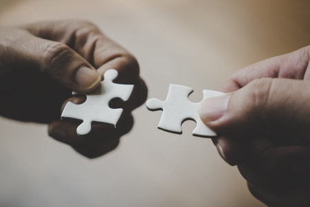 Two hands joining together two jigsaw puzzles