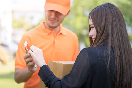 Woman signing on mobile for package deliveryの写真素材