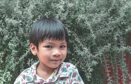 Asian kid is standing in green gardenの写真素材