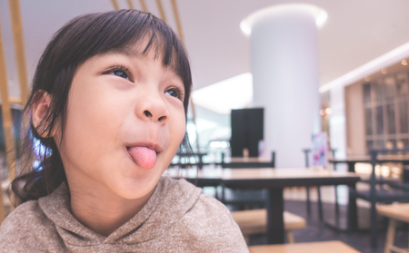 Little Funny Asian girl silly face with tongue outの写真素材