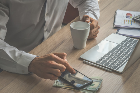 Business man using finger to use mobile phone on working deskの写真素材