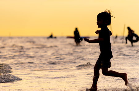 Little kid running on a sand beach silhouetteの写真素材