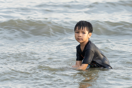 Boy is playing with sand and wave on the beachの写真素材