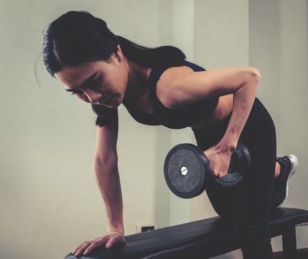 Strong Asian skinny woman is lifting dumbbell in fitnessの写真素材
