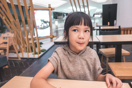 Hungry Funny child licking her lip waiting for food in restaurant.の写真素材