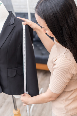 Female fashion tailor is measuring office suit jacketの写真素材