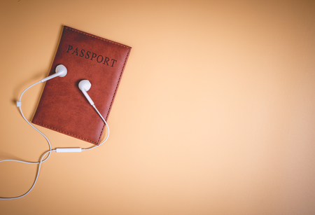 Leather brown passport with white earphones on brown copy spaceの写真素材