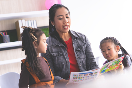 Teacher is reading story book to kindergarten studentsの写真素材