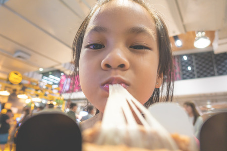 kid is eating sticky cheeze bread in cafeの写真素材