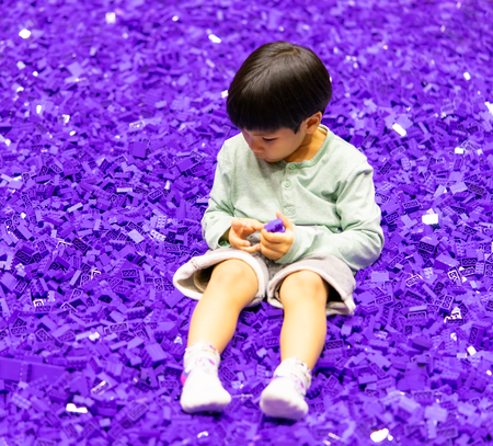 Asina boy playing in a pool full of purple toy blockの写真素材