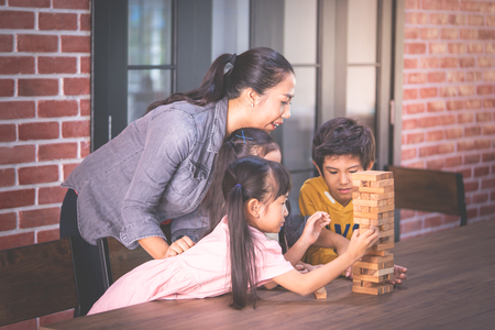 Children is building toy block tower with teacherの写真素材