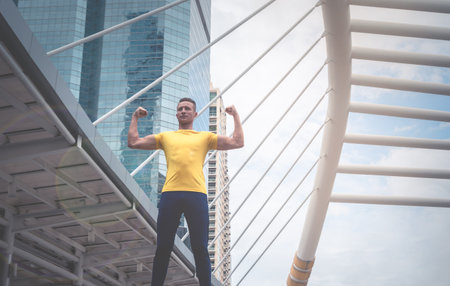Strong Muscular Sport man in yellow is standing in a modern city train station