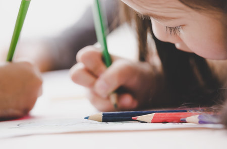 Kid Girl is pencil coloring on paper in living room