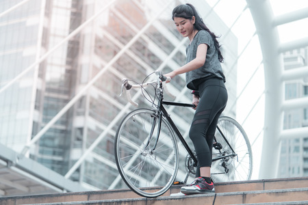 Sport woman is carrying her bike down the stairの写真素材
