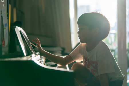 Little Boy is playing with piano and Music Tablet at homeの写真素材
