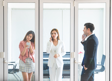 Three young Business people talking on the phone in meeting roomの写真素材