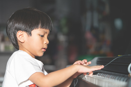 Little Boy is playing with piano and Music Tablet at homeの写真素材