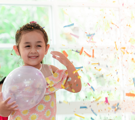 little girl playing and throwing paper in kid partyの写真素材