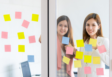 Casual creative business woman is writing ideal and goal on to the windowsの写真素材