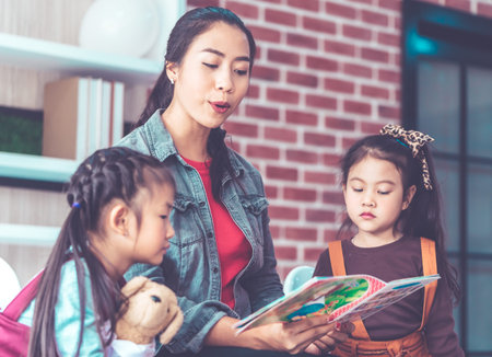 Teacher is reading story book to kindergarten studentsの写真素材