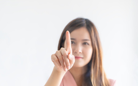 Cute Asian woman is pushing on a touch screen windowsの写真素材