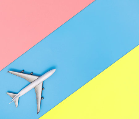 white toy plane on blue and yellow pink background