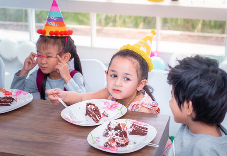Asian children is happy eating her birthday cake in partyの写真素材