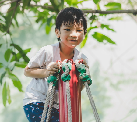 Asian boy is climbing on rope pole in playgroundの写真素材