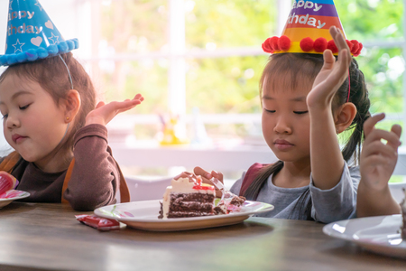 Asian children is happy eating her birthday cake in partyの写真素材