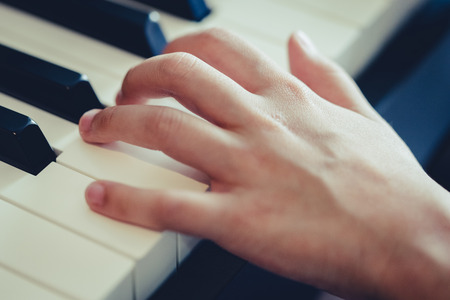 Kid hand pressing on piano key for music conceptの写真素材