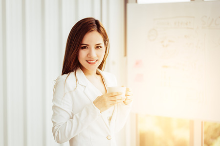Young smiling businesswoman drinking coffee on a morning breakの写真素材