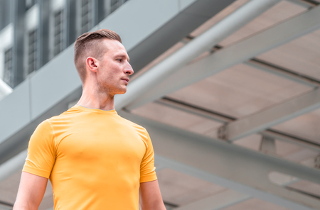 shot of young man in yellow working out in modern city. Healthy male runner working out in modern city.の写真素材