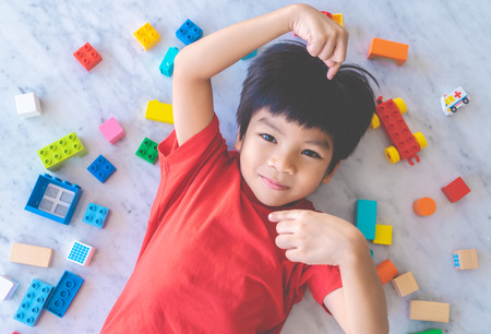 Happy boy surrounded by colorful toy blocks top view.の写真素材